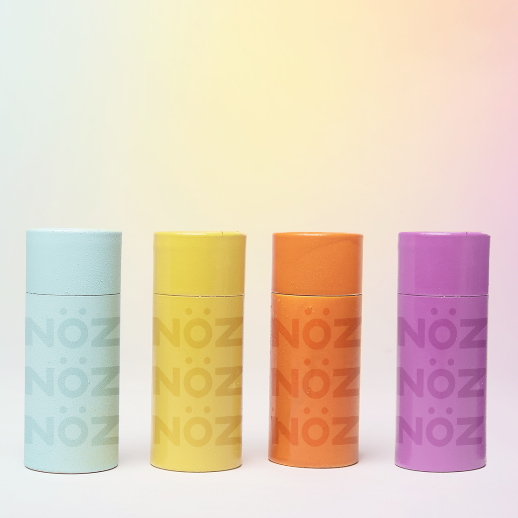 Colorful Nöz products in round rectangular square style container in fours colors bluish green,  yellow,  orange, and purple.